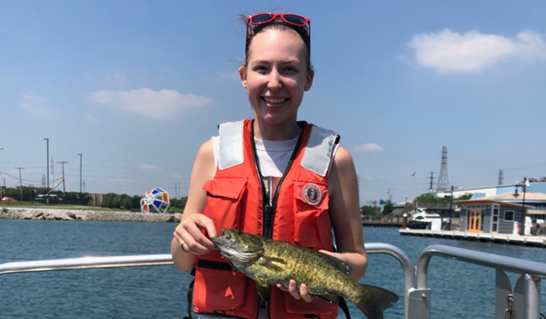 Crystal Hall holds a fish near Lake Michigan
