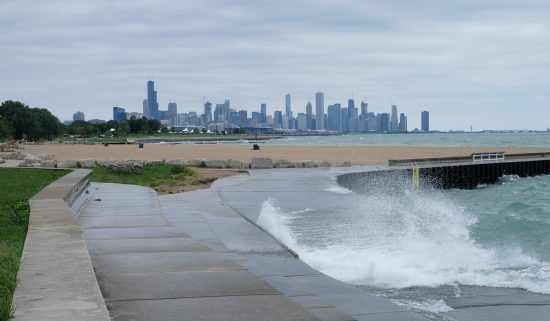 waves crashing over constructed shoreline with Chicago skyline in the background