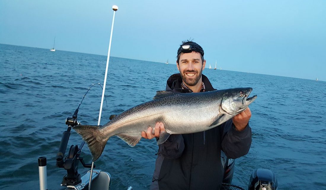 Man on a boat holding a Chinook salmon