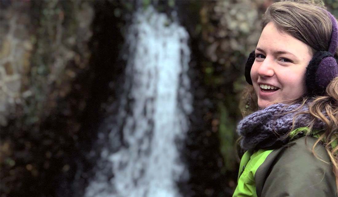 Marissa Cubbage smiles in front of waterfall