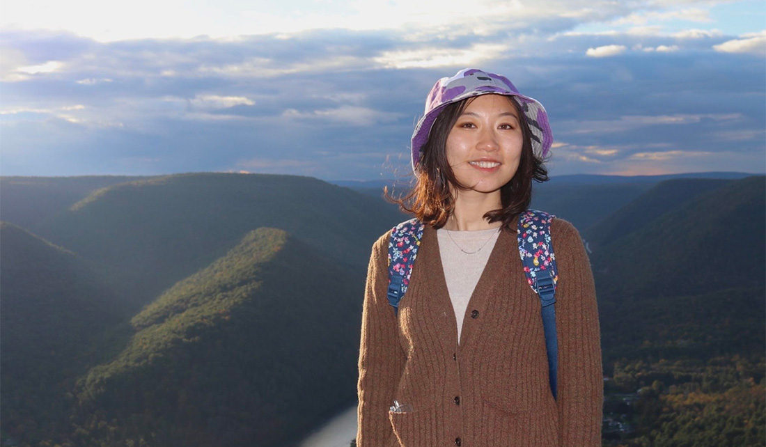 Shuyu Chang poses in front of beautiful mountain landscape