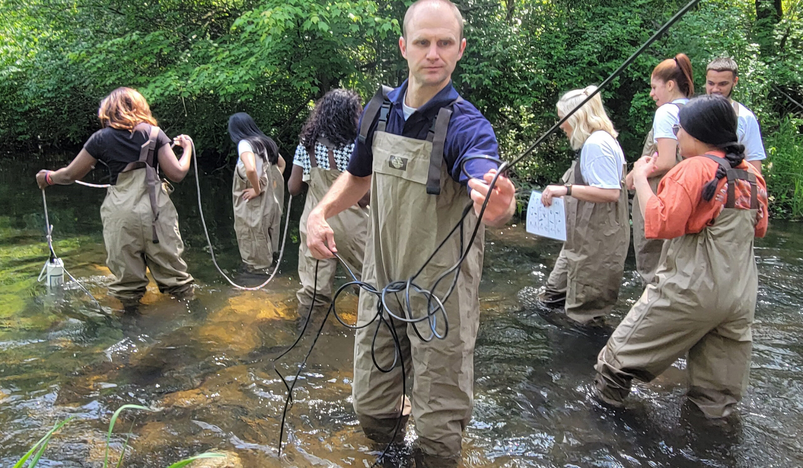 A teacher and his students in Cobus Creek using a hydrolab to engage in water monitoring.