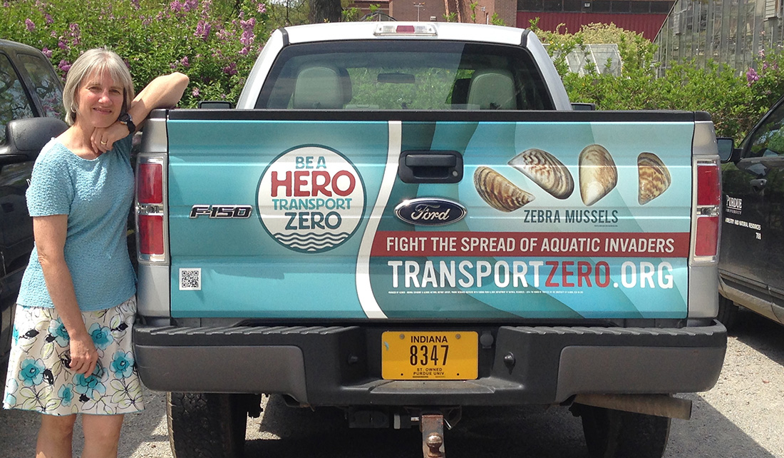 Pat Charlebois stands next to a pick up truck with Be A Hero messaging on it.