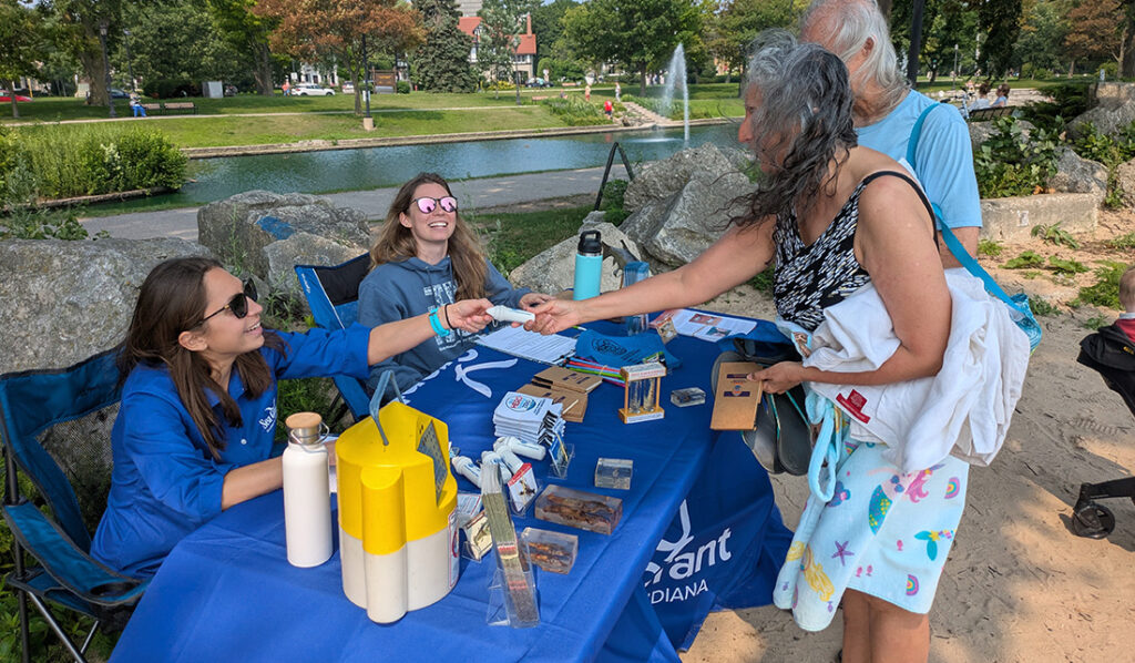Katie O’Reilly and Natalia Szklaruk, who are sitting behind a table with pubs and other sorts resources of are sharing information to a couple.