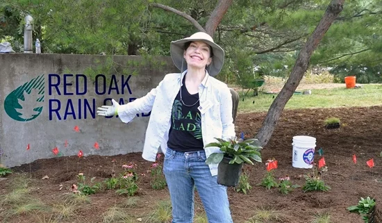 Eliana Brown is holding a potted plant in the rain garden