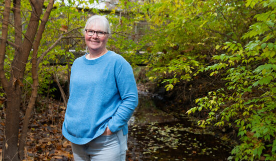 Laura Esman standing in a wooded environment.