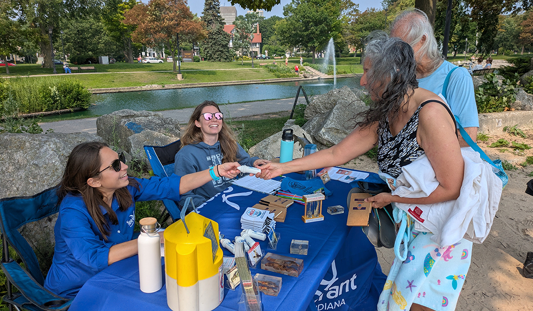 Katie O'Reilly and Natalia Szklaruk are sitting at a table outside sharing info with a man and woman who visited the Rusty Rodeo.